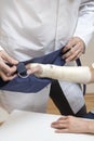 Orthopedist doctor puts a sling on the bandaged woman`s hand